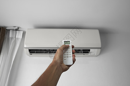 使用遥控器的人的手 手持 rc 和调节安装在白墙上的空调温度 室内舒适温度 健康理念和节能微风气候冷却房间活力护发素控制办公室加图片