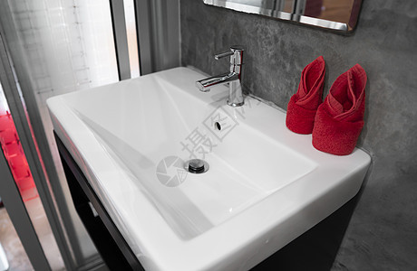 带洗脸盆水槽的现代不锈钢龙头 上面有两条红色毛巾 柜台浴室内部现代 豪华时尚的设计浴室配有混凝土风格的墙壁建筑学公寓制品卫生间镜图片