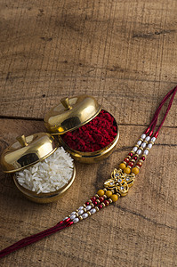 A Rakhi带稻谷 木质背景的Kumkum 印度喜庆背景节日纽带细绳工艺庆典传统珠子宗教文化腕带图片