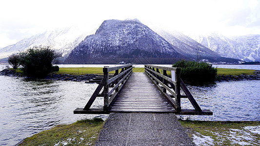Wooden桥通向Hallstat湖风景与雪山 奥地利图片