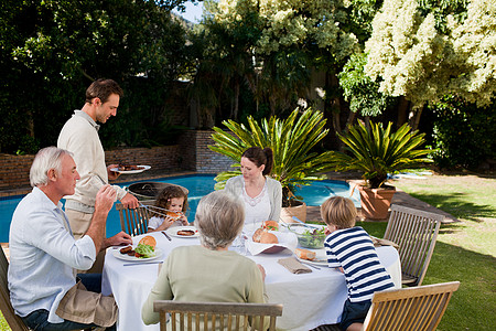 家人在花园里吃饭祖母夫妻果汁男生妻子女儿黑发儿子火腿男人图片
