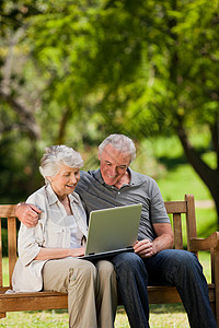 老年夫妇看笔记本电脑公园女性男性笑声座位微笑拥抱女士夫妻农村图片