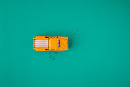 绿色背景的黄色反向汽车小卡车 带有复制空间的顶部视图 平面驾驶旅行古董车轮男生车辆商业运输婴儿保险图片