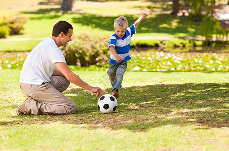 父亲和儿子在公园里踢足球运动绿色男性游戏男生乐趣青年微笑团队场地图片