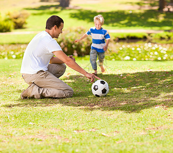 夏天父亲和儿子在足球比赛中一起踢球青年男性闲暇绿色游戏男生场地男人运动公园图片