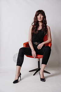 穿着西装的年轻漂亮女孩 坐在红椅子上 白背景图片