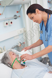 护士给病人戴氧气面具照顾监视诊所关爱枕头趋向制服保护医院女性图片