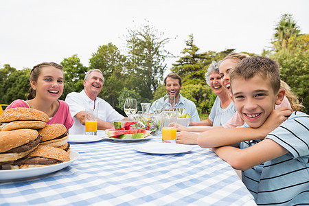 大家庭在野餐桌上户外吃晚饭图片