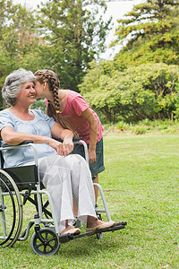 奶奶坐在轮椅上的外孙女亲吻祖母的脸颊图片