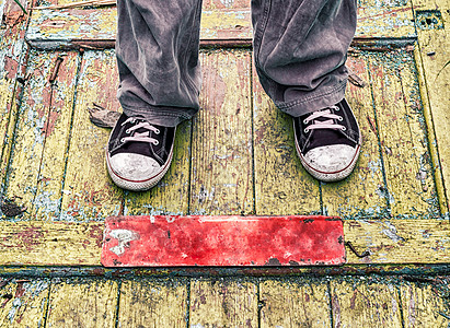 在黄色木制地板上穿旧脏皮鞋的男人的腿红色牛仔裤运动鞋地面街道黑色孤独衣服贫困裤子图片