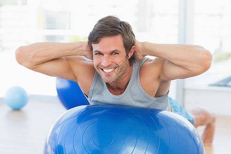 快乐的健身人伸展在运动球上蓝色健身室俱乐部男性平衡闲暇训练活动身体健身图片