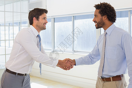 微笑着的年轻商务人士在办公室握手媒体光波背景图片