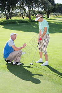 人教他搭档把绿绿色的闲暇帮助高尔夫球晴天快乐女士女性男性阳光休闲背景图片