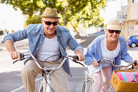 快乐的成熟情侣去城里骑自行车旅行微笑骑术感情休闲退休毯子太阳镜花朵金发女郎女性图片