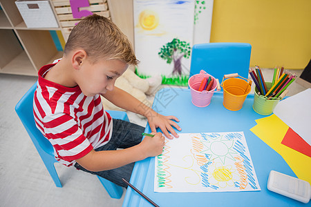 可爱的小男孩在书桌上画画幼儿园微笑艺术班级男生早教铅笔课堂专注快乐背景图片