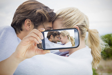 情侣在智能手机上自拍男人微风技术头发快乐马尾辫女性感情电话花园图片
