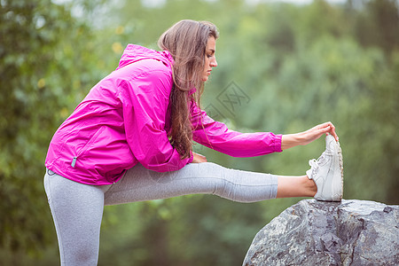 身材适合的女人伸展腿部雨衣娱乐远足环境勘探冒险女性农村冒险家绿色背景图片