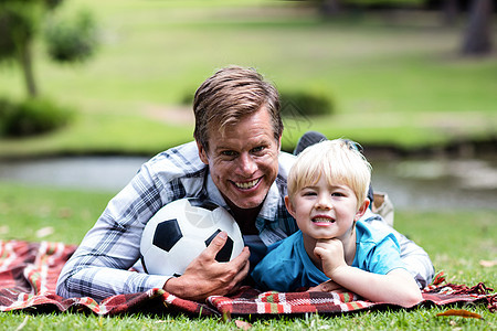 父亲和儿子躺在公园里阳光草地休闲闲暇农村游戏男人喜悦感情活动图片