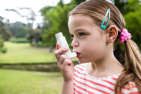 使用哮喘吸入器的女孩绿地服装休闲呼吸金发女郎哮喘病公园病痛疾病女性图片