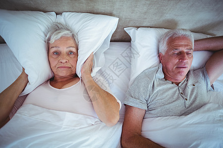妻子用枕头挡住耳朵 而丈夫在床上打呼噜图片