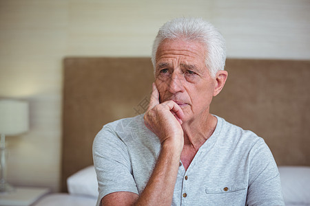 坐在床上深思熟虑的老人沉思窗户下巴男人紧张男性压力老年人退休睡衣图片