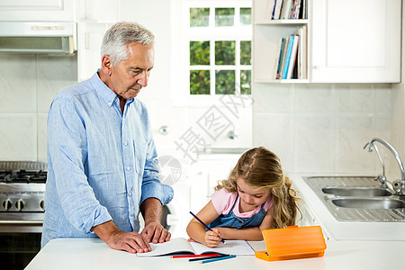 女孩和爷爷一起在桌边学习图片