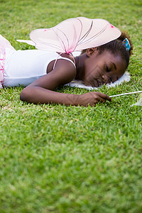穿着童话服 睡在草地上的可爱的混合种族女孩睡眠阳光天空午睡魔法棒仙女裙说谎女性黑色农村背景图片