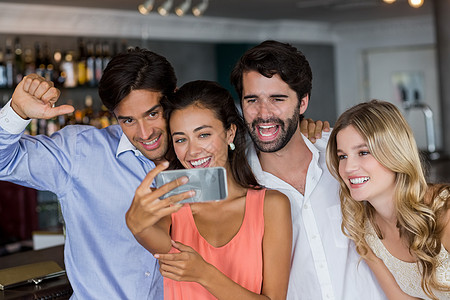 一群朋友玩自拍微笑餐厅享受技术庆典酒吧娱乐男性快乐照片背景