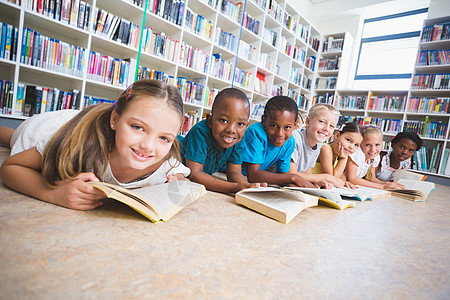 坐在图书馆地板阅读书上微笑的学校学生学习混血童年孩子们休闲地面小学生教育快乐瞳孔图片