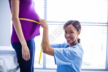 测量孕妇在病房腹部的医生肖像孕妇装怀孕体格等待医院卷尺卫生服务访问女性图片