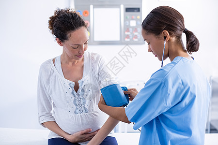 医生检查孕妇的血压孕妇装磨砂膏怀孕治疗体格访问医学女性咨询诊所背景图片