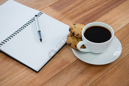 猴菇饼干带笔和黑咖啡的开放日记热饮职场桌子屏幕咖啡杯智力咖啡创造力检查螺旋背景