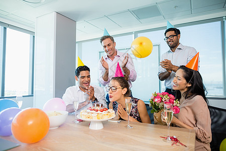 欢庆妇女生日的微笑的同事们女士享受休闲桌子公司气球奇观男性商业快乐图片