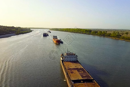 一艘货船沿河漂浮 货物船运河旅游森林油船天空运输送货贸易船运载体图片