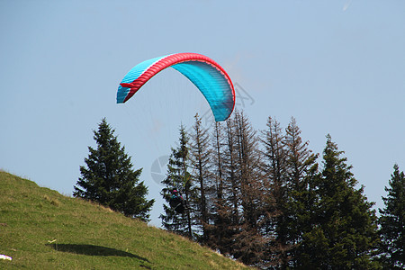 正在向高山的某处滑翔降落伞娱乐活动头盔冒险潜水空气风险蓝色跳伞员图片