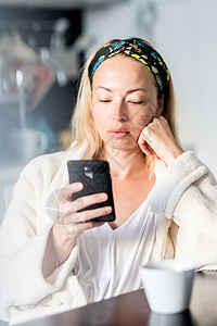 手机银行卡家里美丽的女性 穿着白浴袍感到舒服 自己花点时间 喝早咖啡及早上在手机设备上读新闻   info浴衣饮料互联网成人乐趣工作技术闲背景