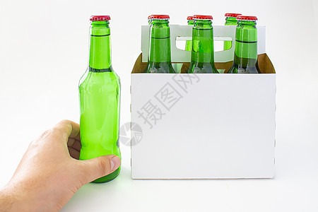 一个人拿着啤酒和六包绿色啤酒瓶 被白种背景孤立一身的图片