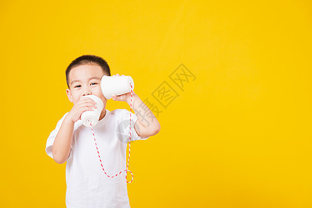 小男孩微笑 站着如此快乐的打纸手艺白色黄色讲话男生玩具童年讨论动作电话男孩们图片