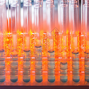 在暖橙色背景上装有蓝色液体的玻璃试管橙子生物样本烧瓶科学制药科学家烧杯测试乐器背景图片