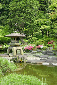 垂直的日本户外石器灯笼 在金园中季节公园植物农村池塘花园反射云杉土地花朵图片