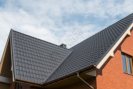 覆盖有瓷砖效果 PVC 涂层棕色金属屋顶板的现代屋顶建筑学住宅平房材料建筑制品天空橙子卵石技术图片