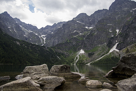 美丽的夏季高山湖景被绿树覆盖 前面有石头 天空中有云彩 山在水中的倒影 水晶般清澈的水 欧洲 阿尔卑斯山池塘季节叶子森林国家风景图片