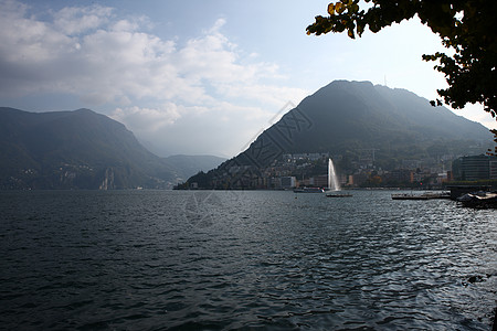 城市和山卢加诺湖 山岳和喷泉背景