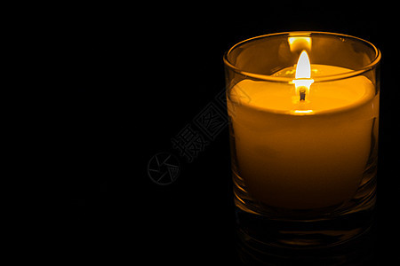 在黑暗背景的玻璃罐中蜡烛煤渣淡黄色燃烧黑色烛火火焰房子烛光风格烛台图片