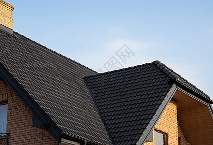 棕色金属瓦屋顶 屋顶金属板 现代类型的屋顶材料 屋瓦的屋顶映衬着蓝天 建筑床单阳光阁楼控制板房子窗户维修建造角落建筑学图片