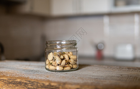 开心果放在一个罐子里 放在一张白色的老式桌子上 背景是厨房 开心果是一种健康的素食蛋白质营养食品 在土气老木头的开心果榛子饮食小图片