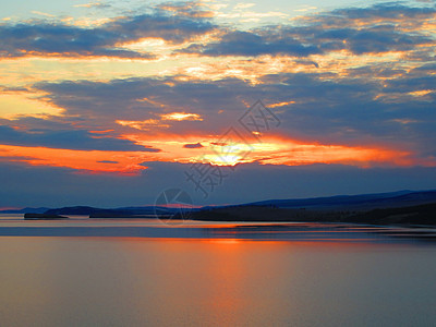 Baikal湖云层的橙色日落 与平静水的反射图片