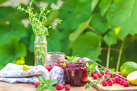 生锈木制桌边的草莓果酱和新鲜树莓叶子覆盆子食物美食桌子玻璃晴天季节甜点早餐图片