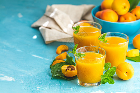蓝色冲浪时阳光明亮的新鲜 健康的杏汁杯子饮食桌子营养收成橙子叶子玻璃树叶团体甜点图片