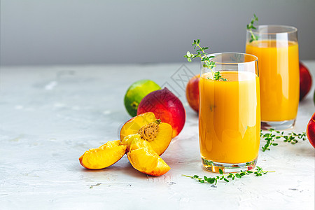 一杯新鲜健康的桃子冰水杯或浅灰色圆锥上的果汁木头叶子甜点食物橙子饮食饮料玻璃营养牛奶图片